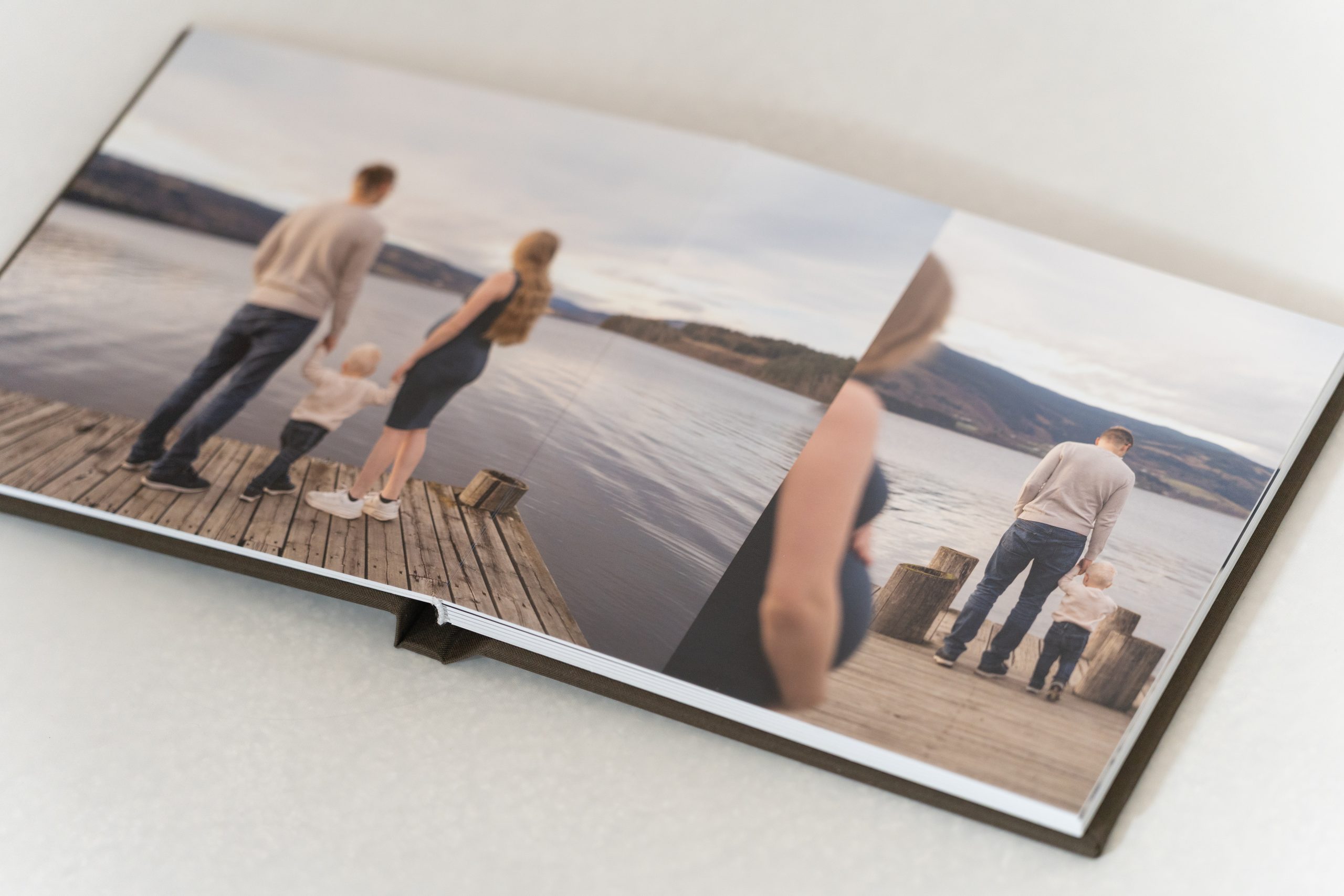 Åpent kvalitetsalbum med gravid- og familiebilder fra fotografering ved vannet.