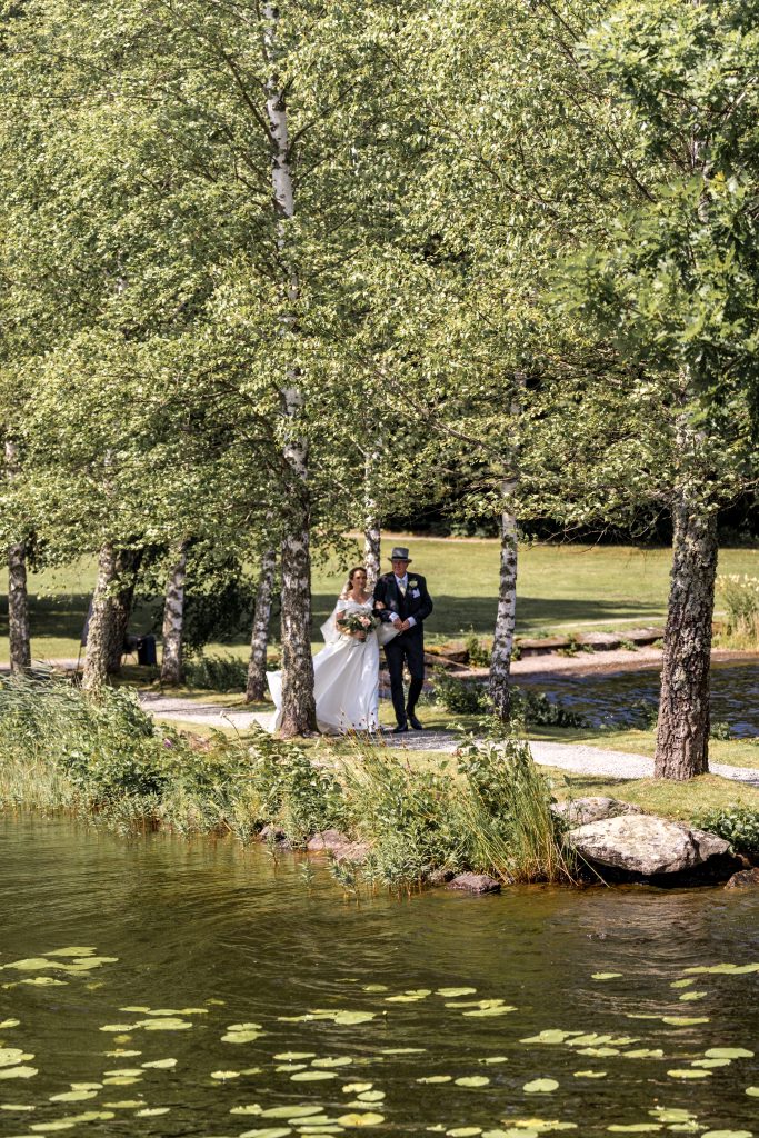 Brud går sammen med følge langs vannet før vielsen på Baldersnäs Herregård
