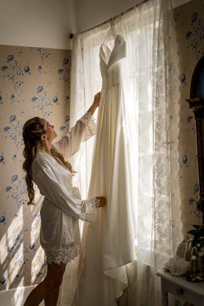 Brud ser på brudekjolen som henger i vinduet på Baldersnäs Herregård